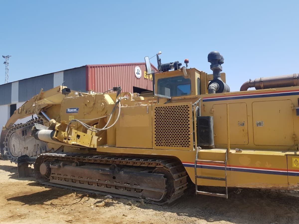 Un gran tractor amarillo está estacionado frente a un edificio.