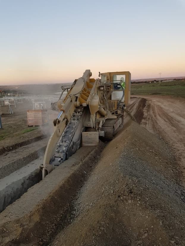 Una excavadora está cortando un agujero en el suelo en un camino de tierra.