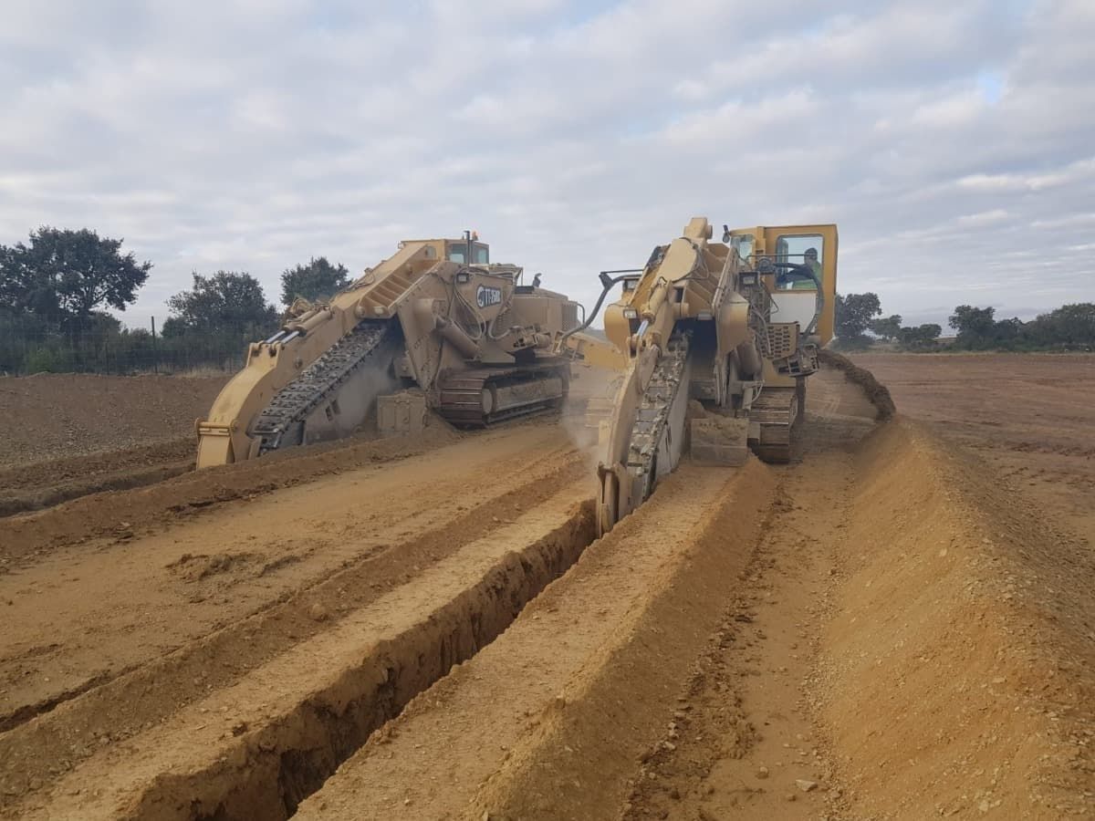Dos excavadoras están trabajando en un camino de tierra.