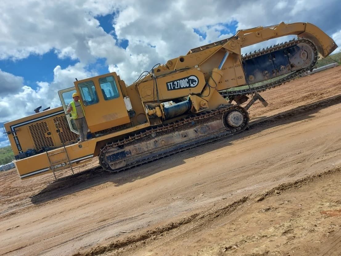 Una gran excavadora amarilla avanza por un camino de tierra.