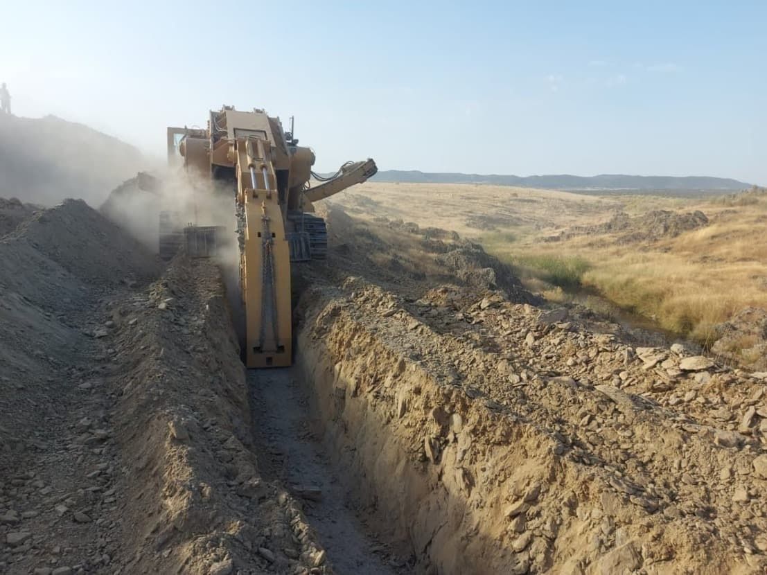 Una excavadora está cavando una zanja en la tierra