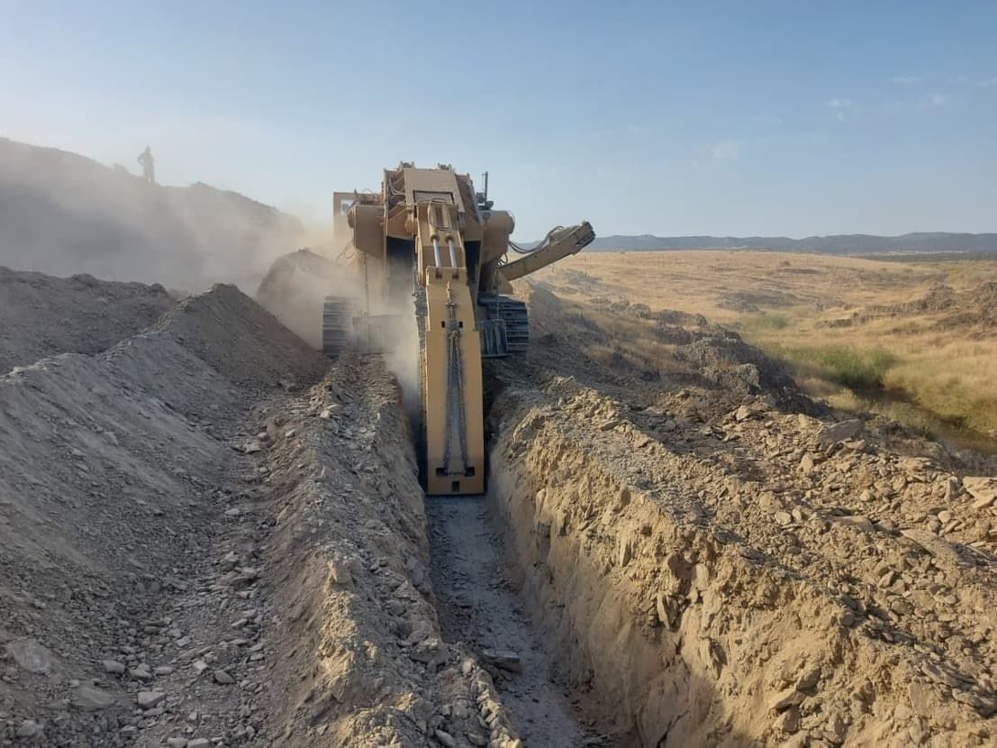 Una excavadora está cavando una zanja en la tierra.