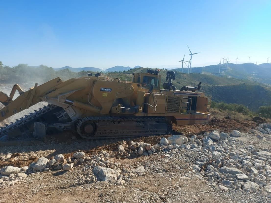 Una excavadora está sentada en la cima de una colina rocosa.