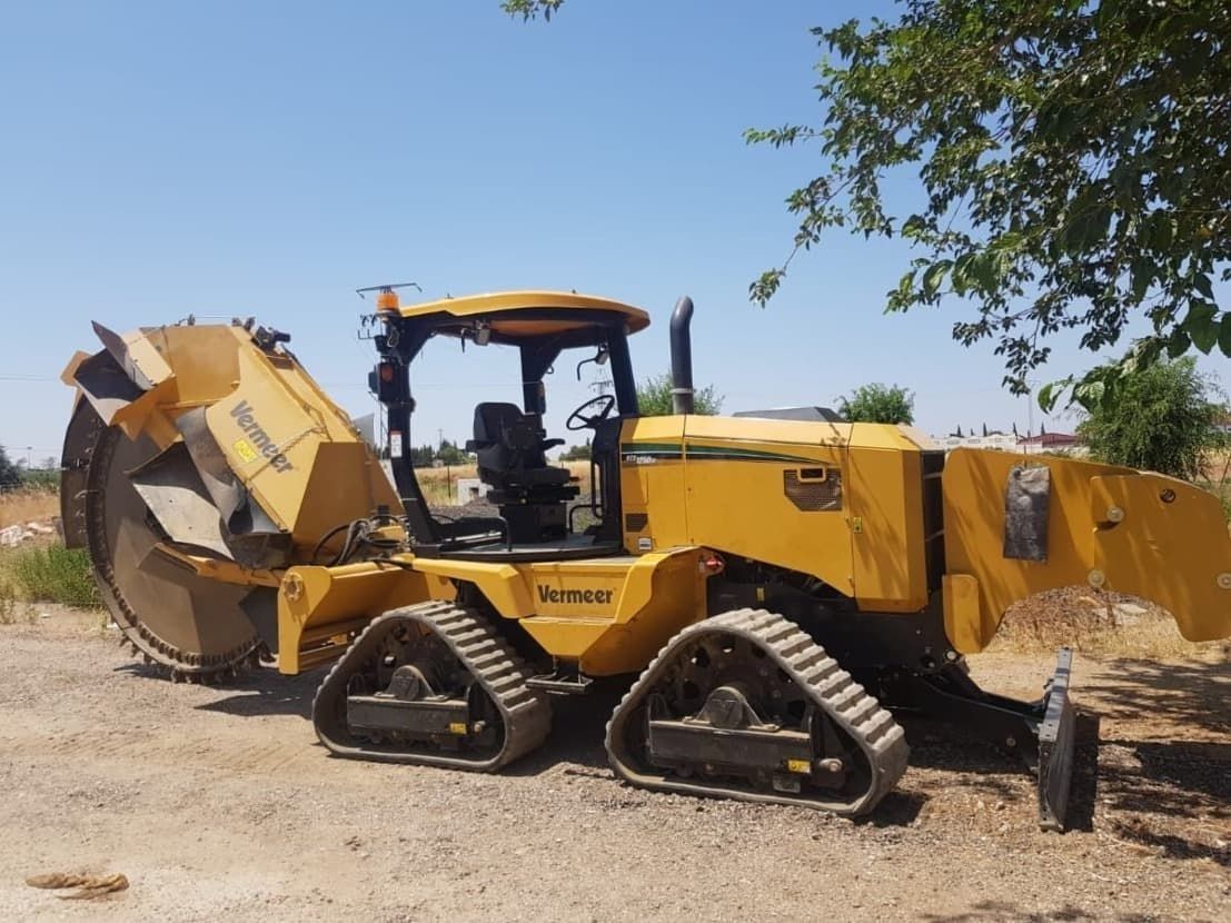 Un tractor amarillo está estacionado en un campo de tierra.