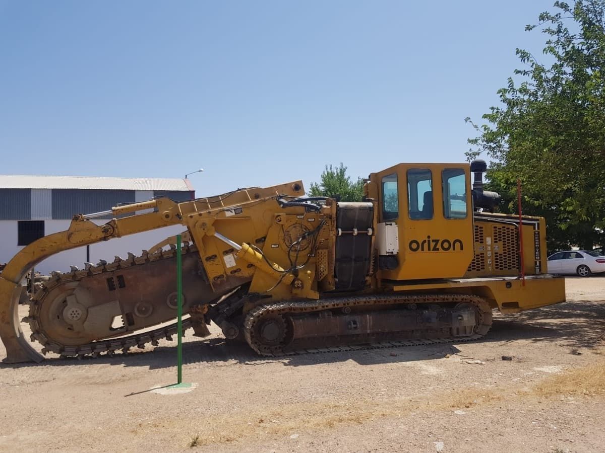 Un tractor orlzon amarillo está estacionado en un lote de tierra.