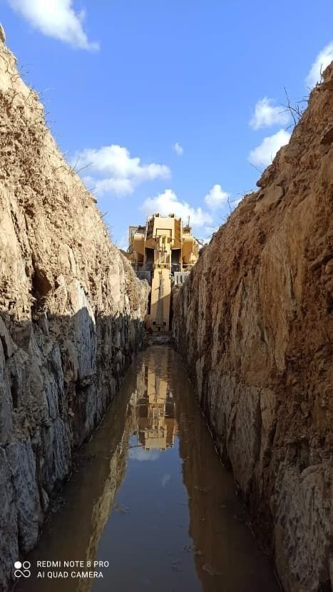 Un río fangoso entre dos acantilados rocosos con un edificio al fondo.
