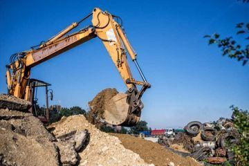 Una excavadora está cavando un hoyo en un montón de tierra.