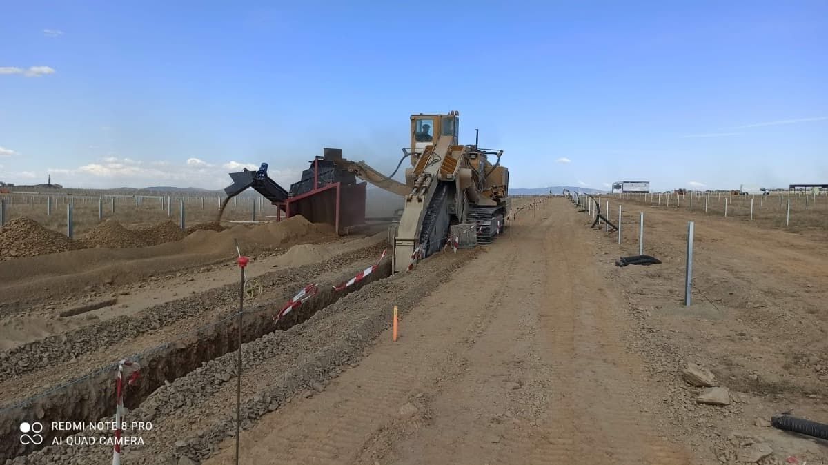 Una excavadora está trabajando en un camino de tierra.