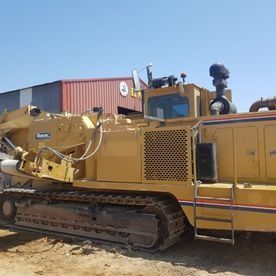 Una gran excavadora amarilla está estacionada en el suelo frente a un edificio.