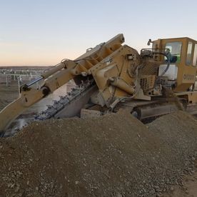 Una excavadora está encima de un montón de tierra.