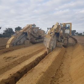 Un par de tractores están trabajando en un camino de tierra.