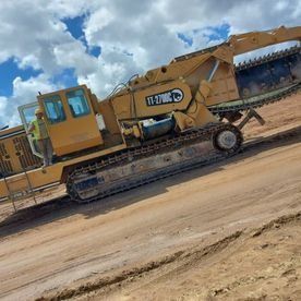 Una excavadora amarilla avanza por un camino de tierra.