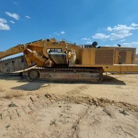 Una gran excavadora amarilla está sentada encima de un campo de tierra.
