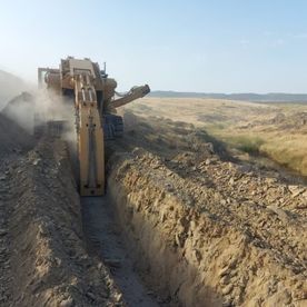 Una excavadora está cavando una zanja en la tierra.