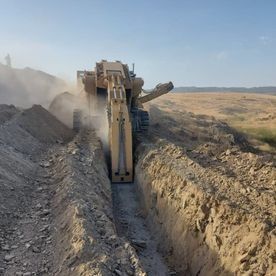 Una excavadora está cavando una zanja en la tierra.