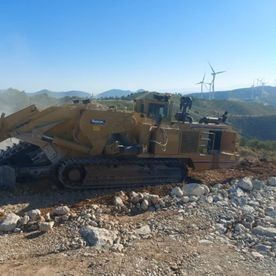 Una excavadora está parada en la cima de una colina de tierra.