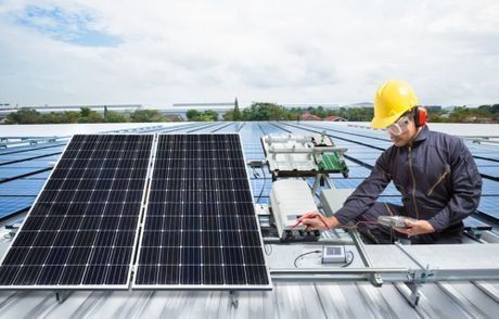 Un hombre está trabajando en un panel solar en el tejado de un edificio.