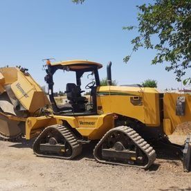 Un tractor amarillo con orugas está estacionado al costado de la carretera.