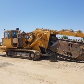 Una gran excavadora amarilla está estacionada al costado de un camino de tierra.