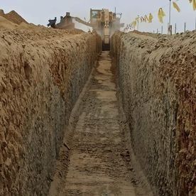 Una excavadora está cavando una zanja en la tierra.