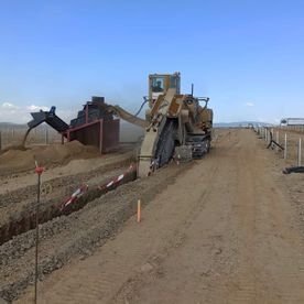Una excavadora está cavando un hoyo en el suelo en un camino de tierra.