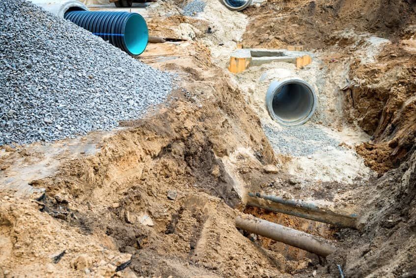 Un montón de grava y tuberías en el suelo de un sitio de construcción.