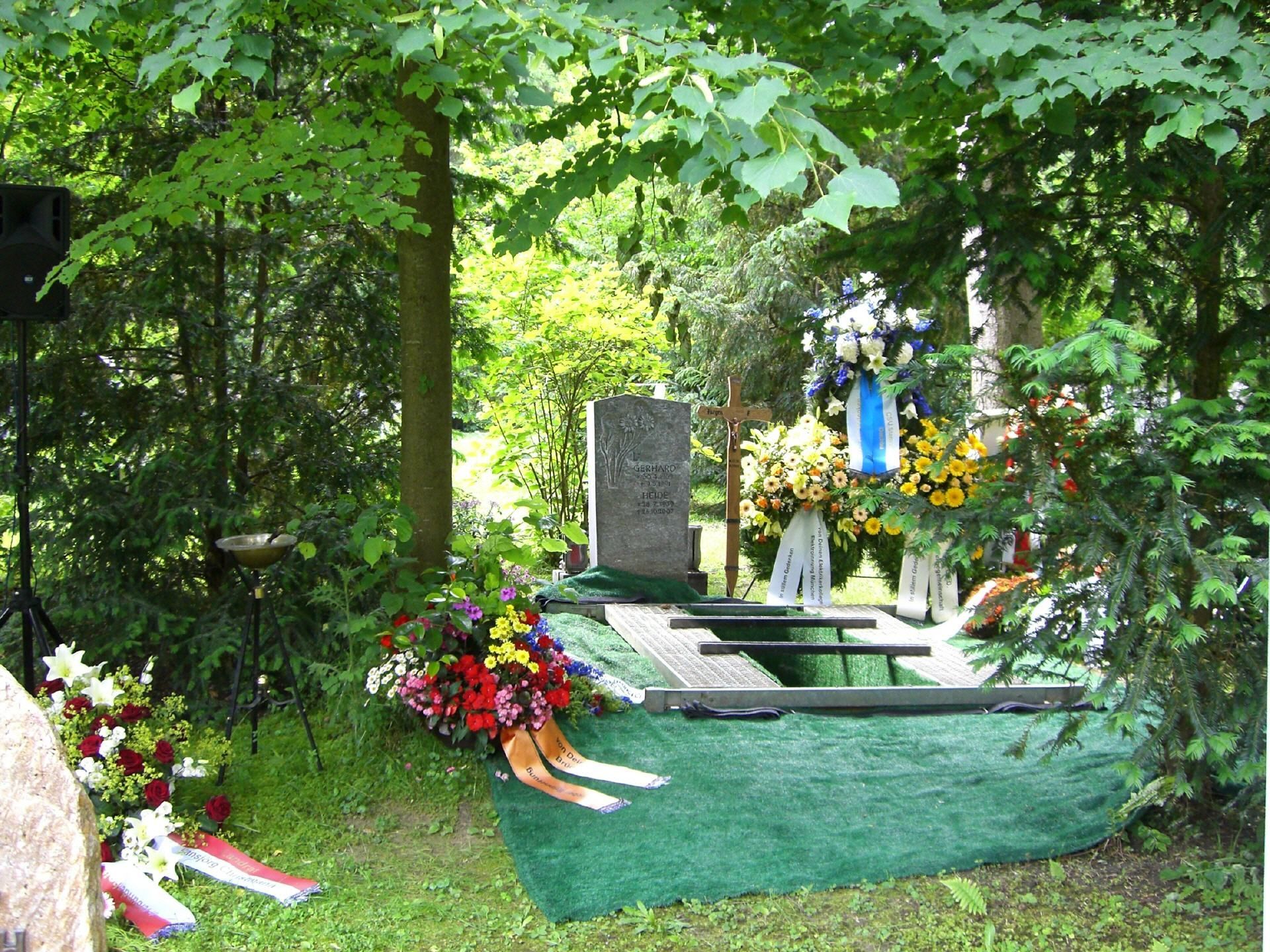 Ein Grab mit Blumen und Bändern im Wald