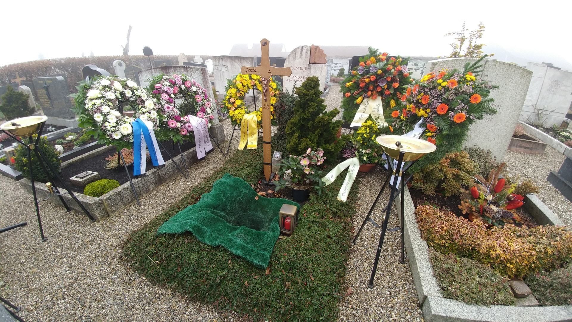 Ein Friedhof mit Blumen und einem Kreuz in der Mitte