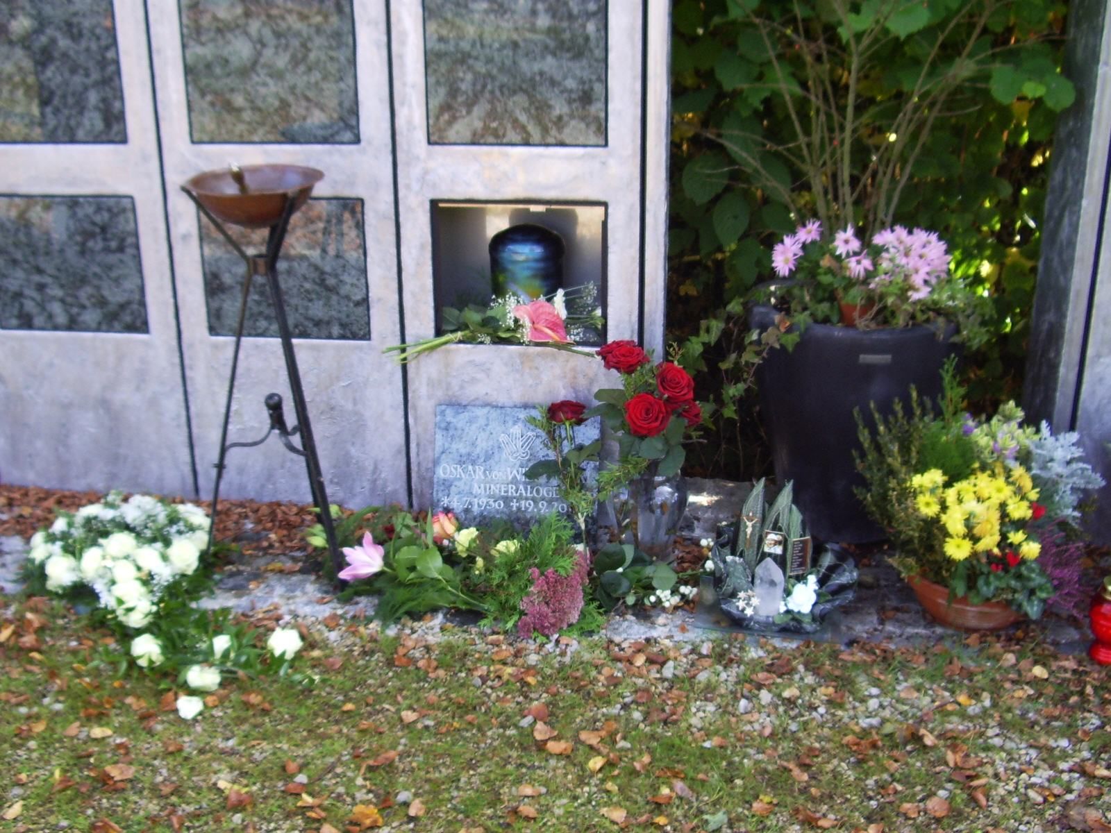 Ein Grab mit Blumen und Kerzen vor einer Tür