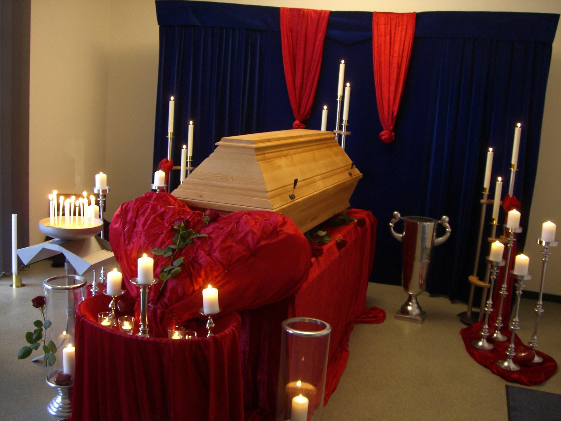 Ein Sarg steht auf einem Tisch mit Kerzen drumherum