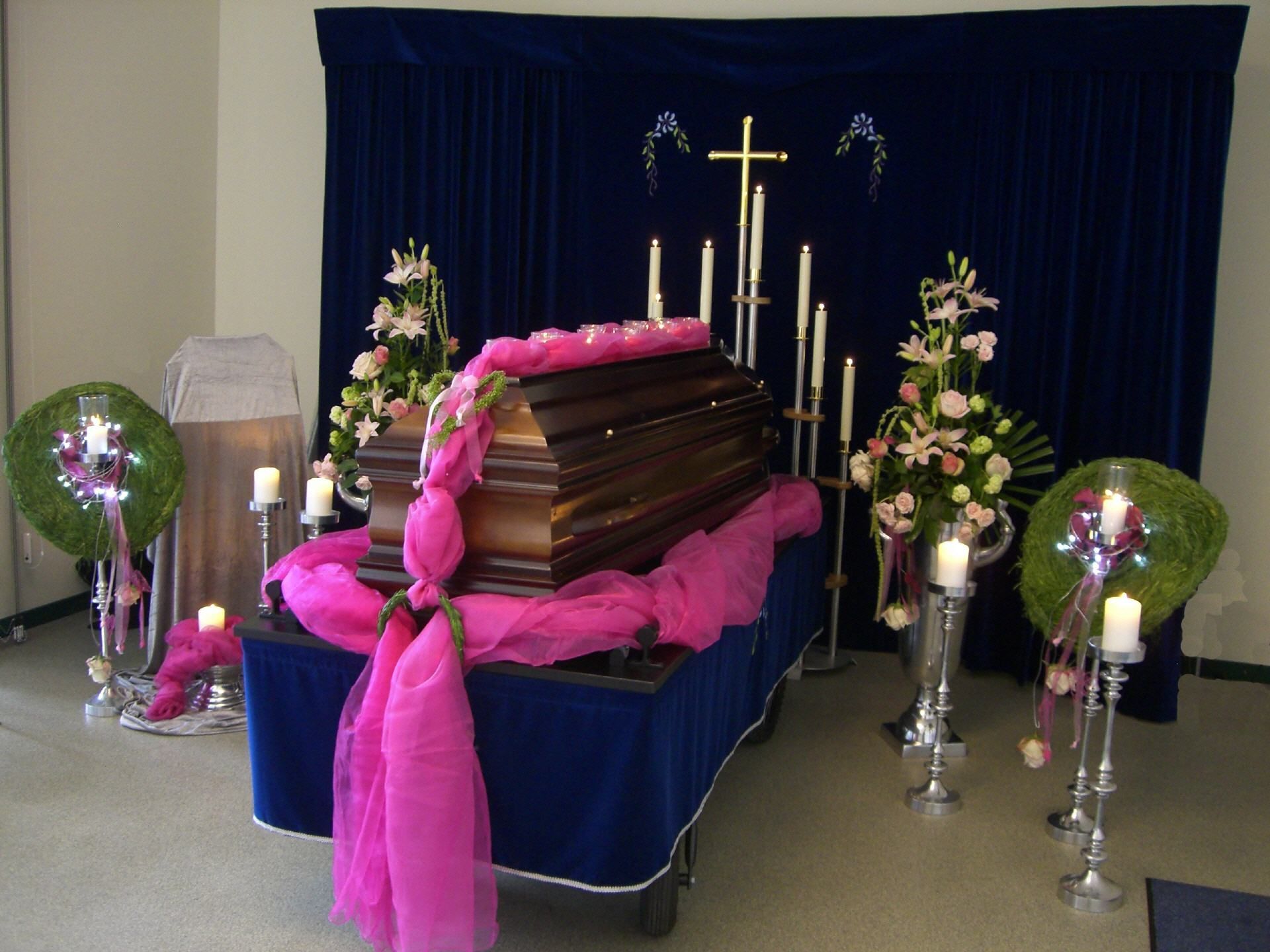 Ein Sarg ist mit rosa Blumen und Kerzen geschmückt