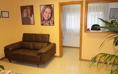 Una sala de espera con un sofá y cuadros en la pared.