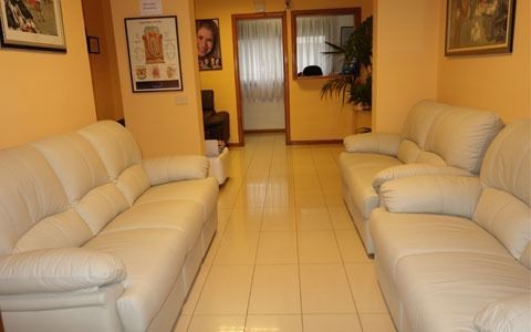 Una sala de espera con dos sofás blancos y un cuadro en la pared.