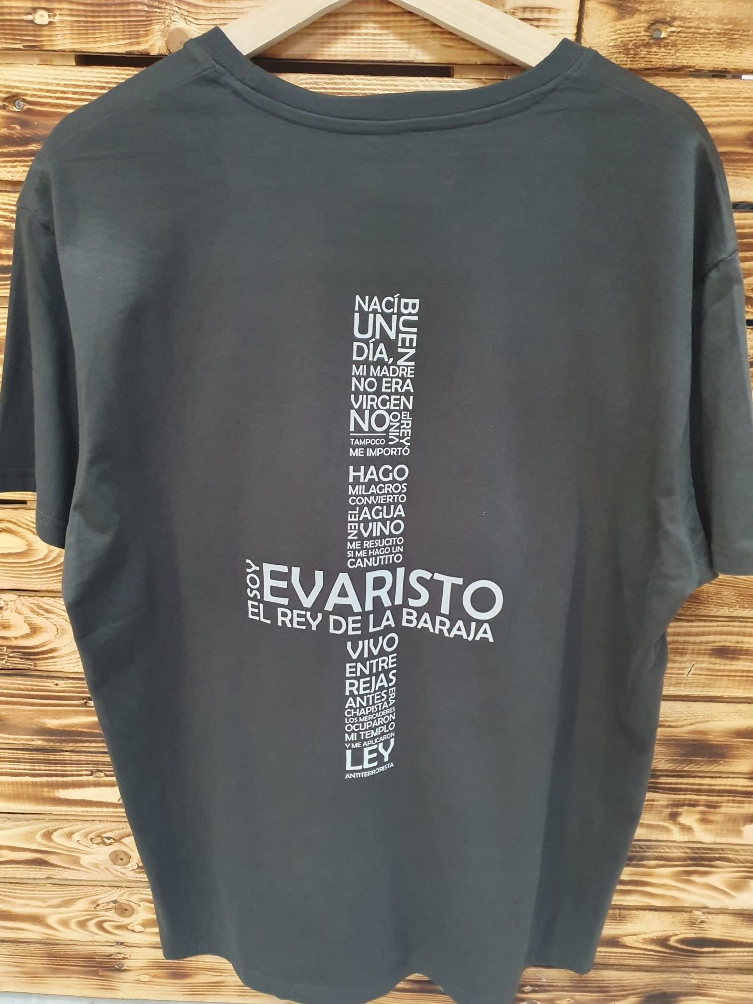 Una camiseta negra con una cruz cuelga de una percha de madera.