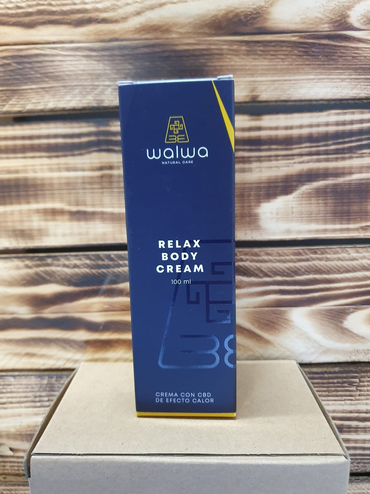 Una caja de crema corporal relajante reposa sobre una mesa de madera.