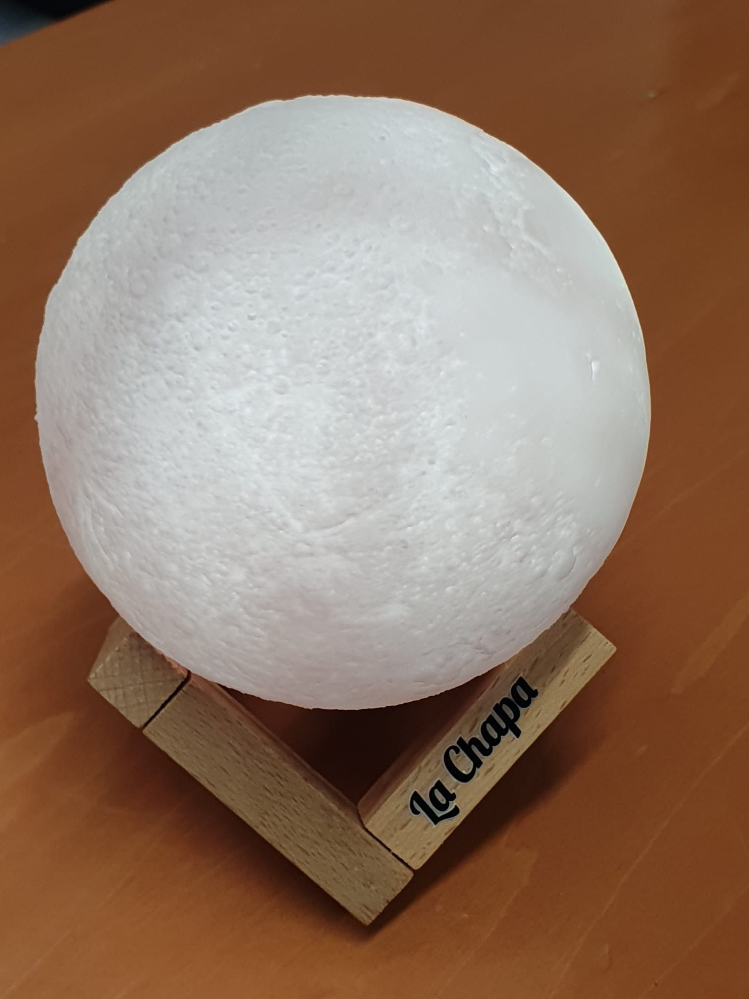 La lámpara A La Chapa está sobre una mesa de madera.