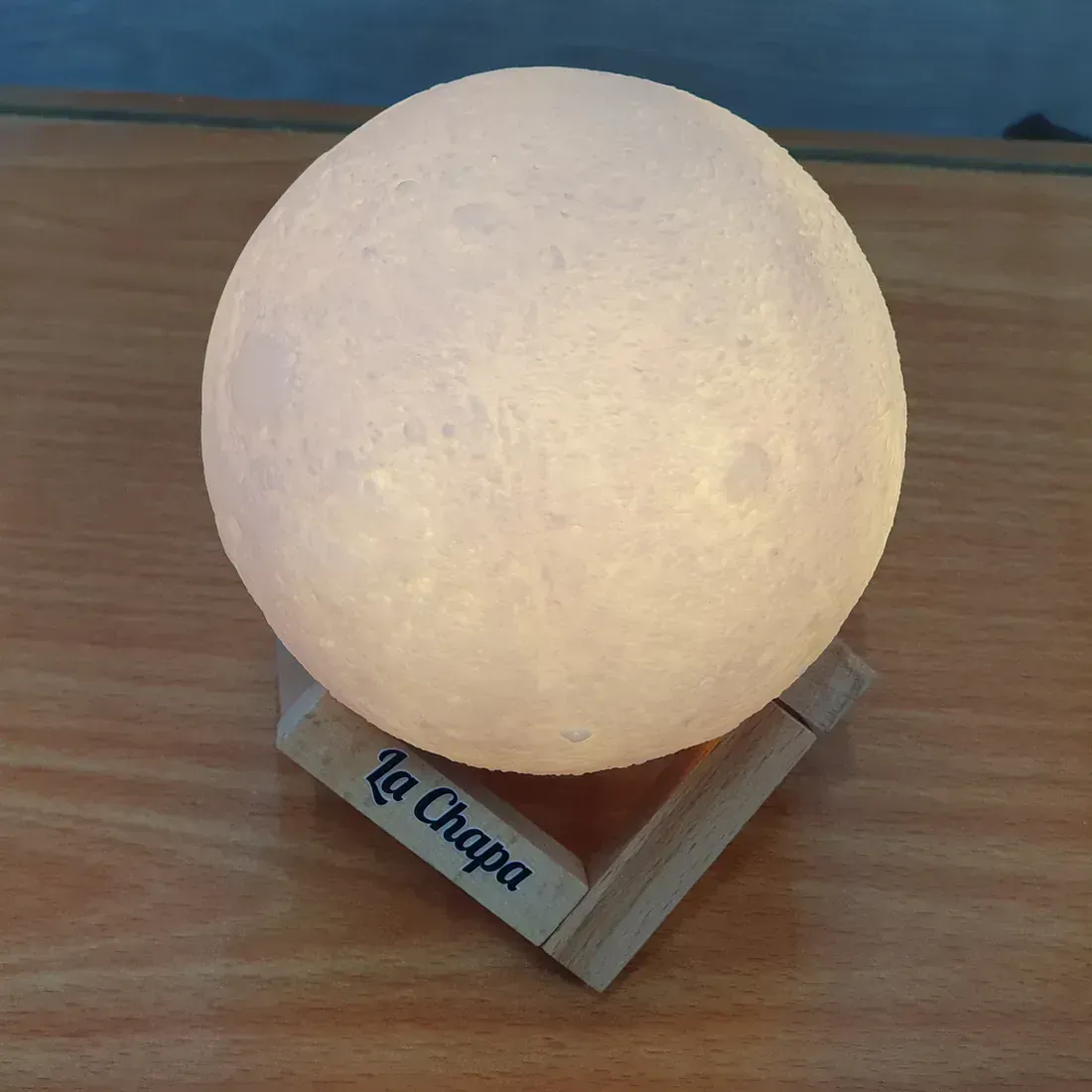 La lámpara A La Chapa está sobre una mesa de madera.