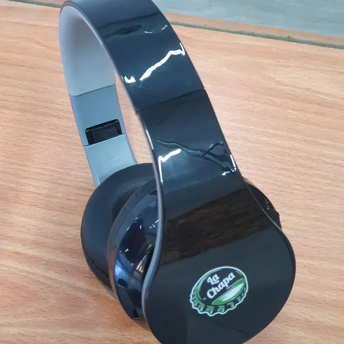 Un par de auriculares La Chapa están sobre una mesa de madera.