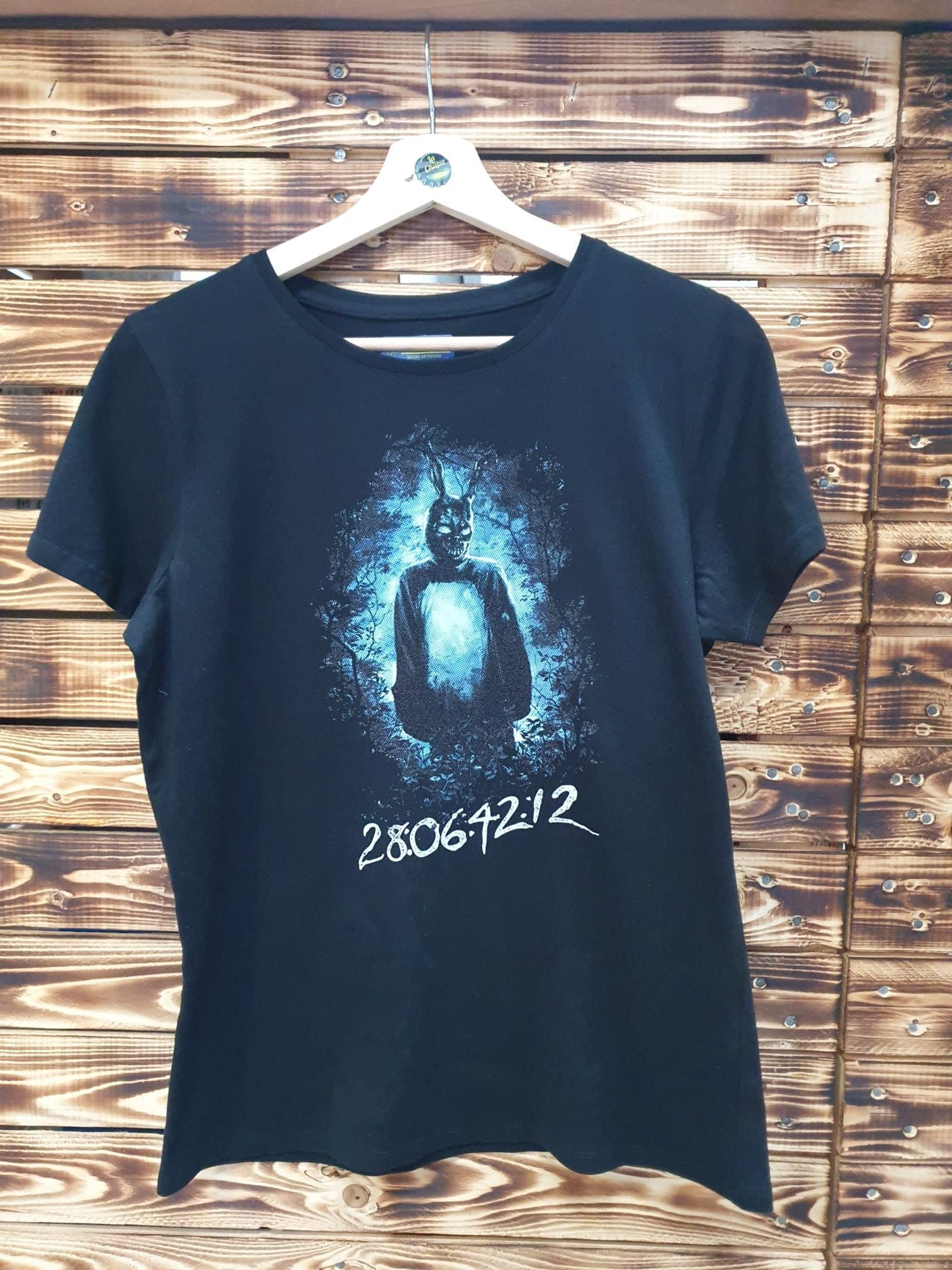 Una camiseta negra está colgada en una percha de madera.