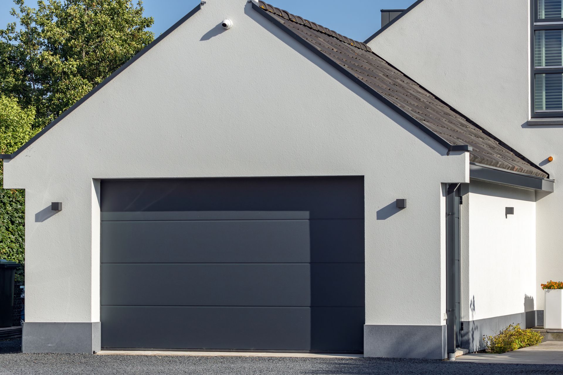 Maison moderne avec porte de garage enroulable et toiture en pente.