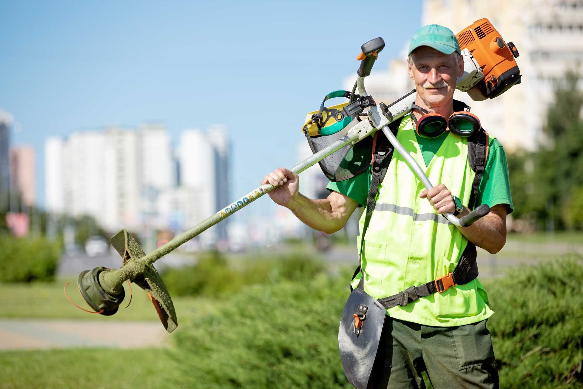 Un jardinier professionnel qui tient un rotofil dans une espace vert urbain