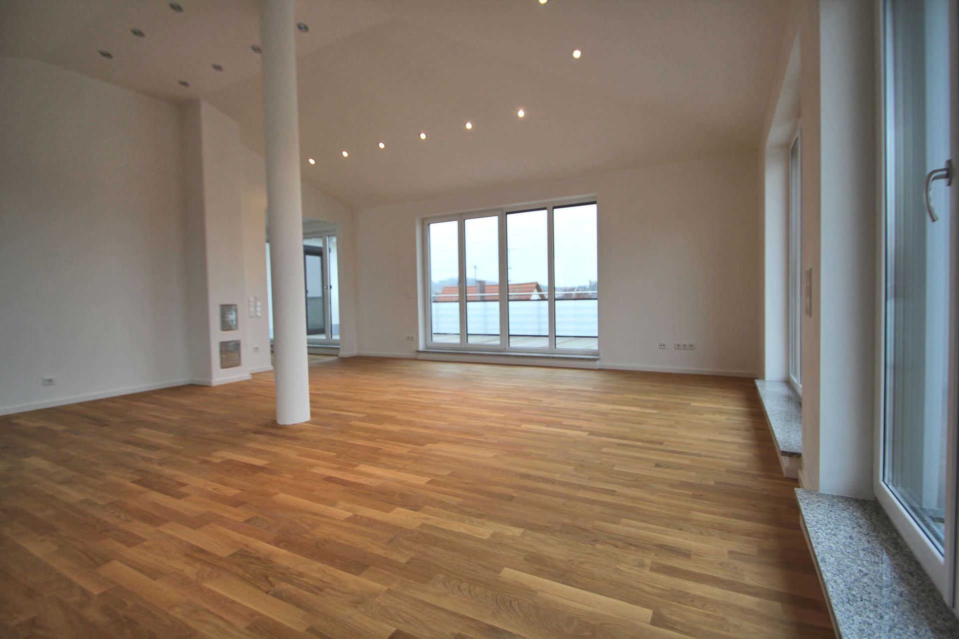 Ein leerer Raum mit Holzboden und vielen Fenstern