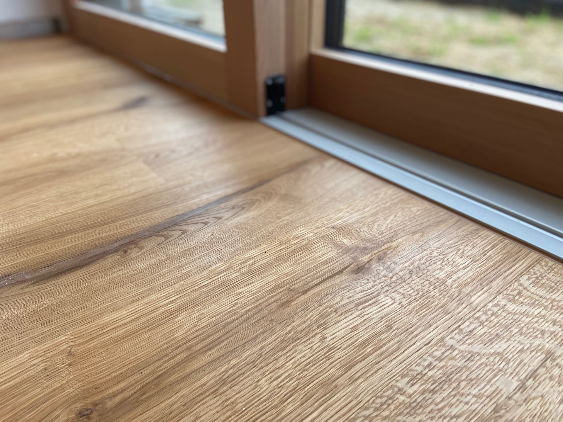 Eine Nahaufnahme eines Holzbodens neben einem Fenster