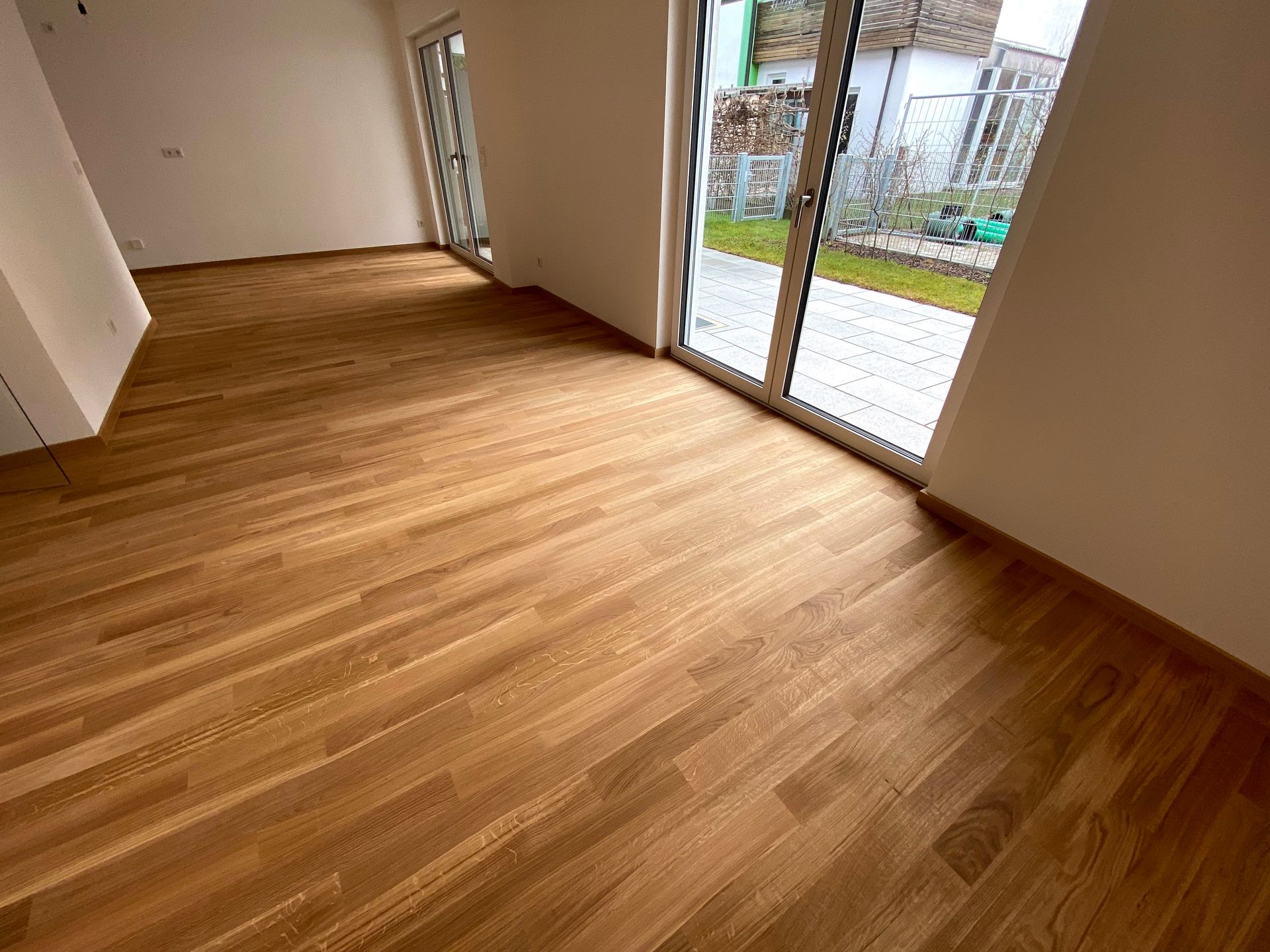 Ein Wohnzimmer mit Holzboden und großen Fenstern