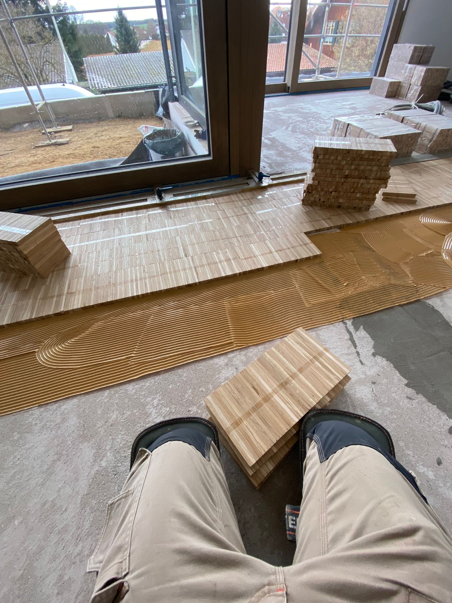 Ein Mann sitzt auf einem Holzboden und trägt ein Paar Knieschoner