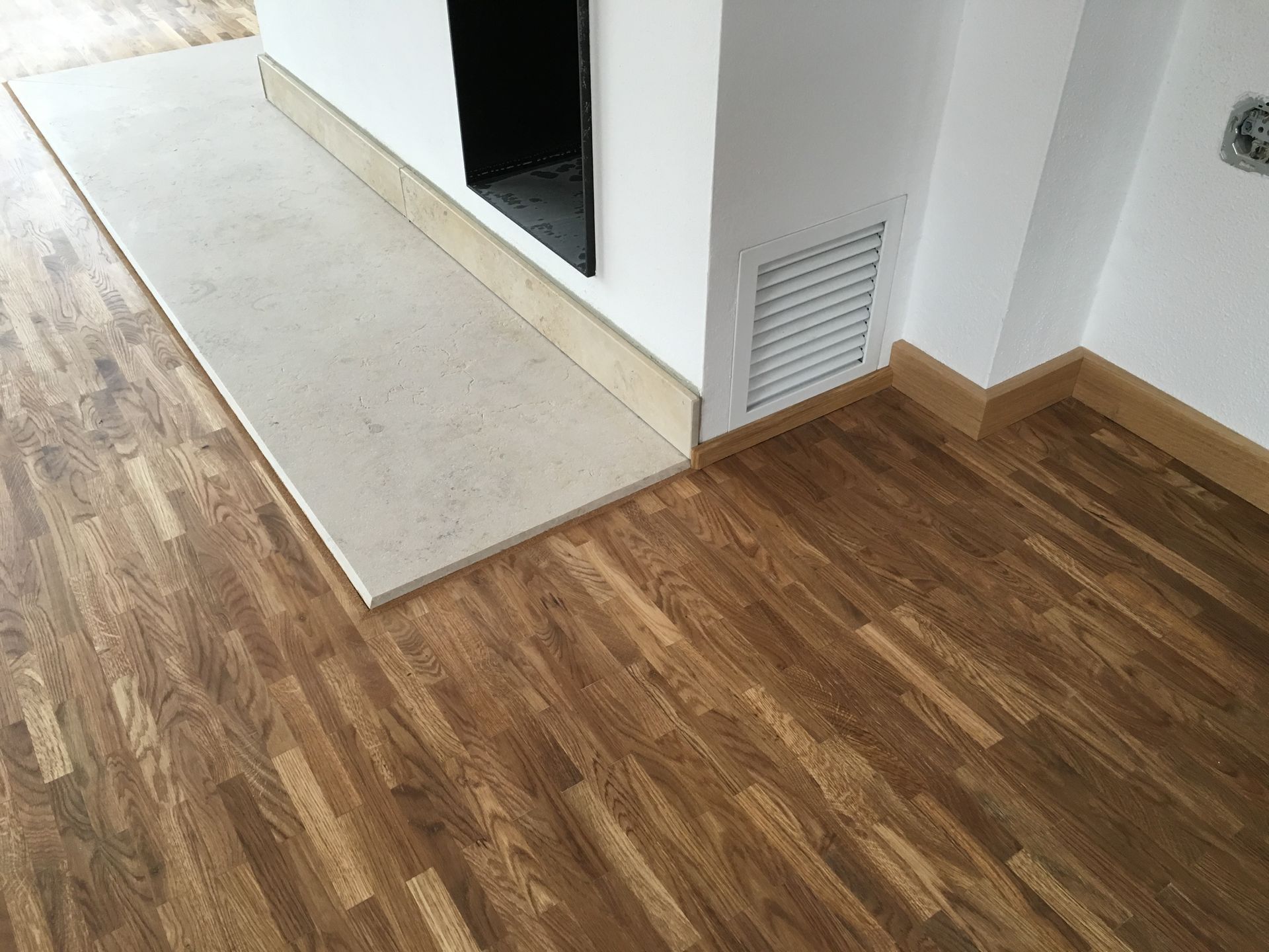 Ein Holzboden in einem Raum neben einem Kamin