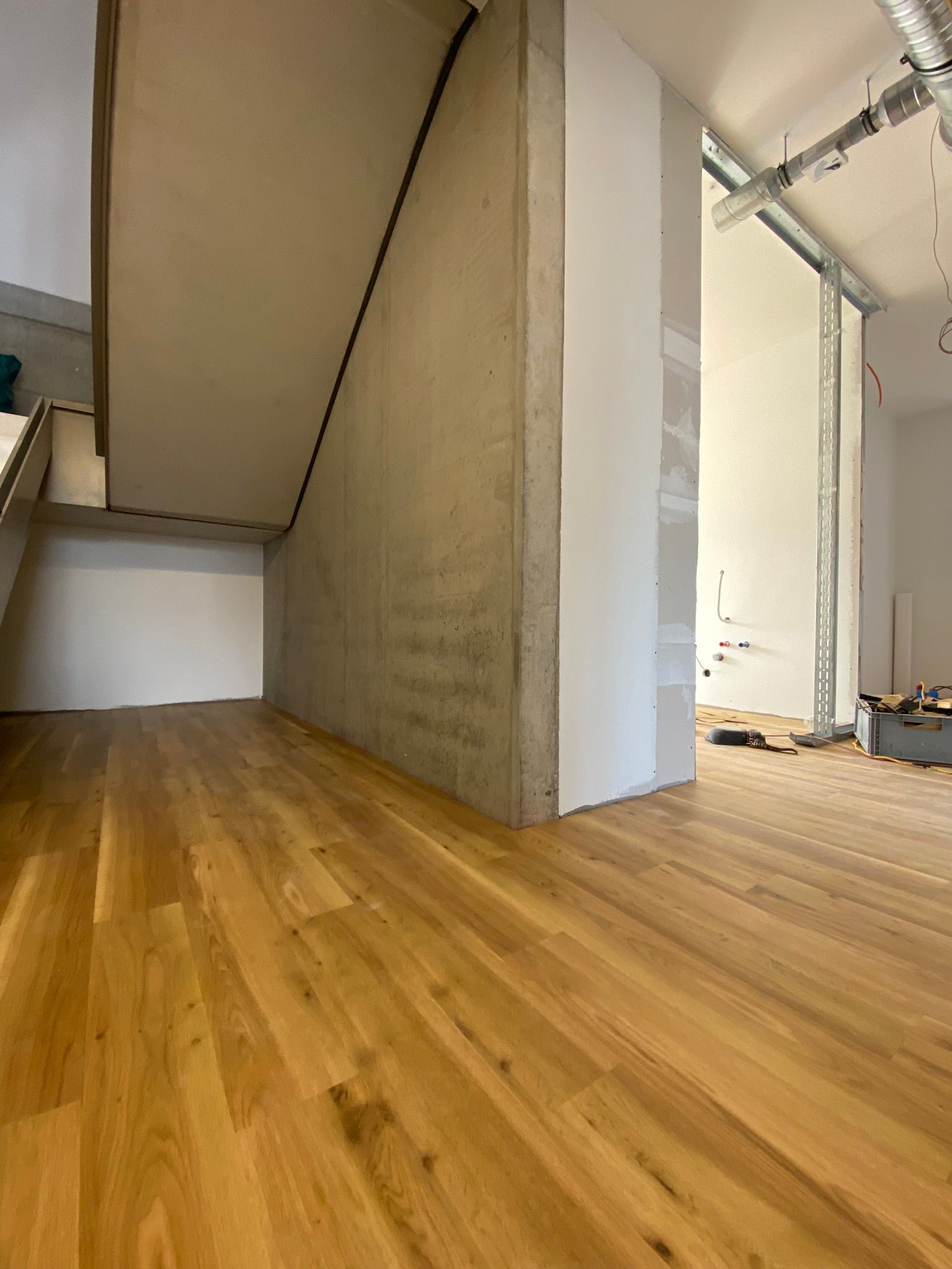 Ein Raum mit Holzboden und Betonwänden