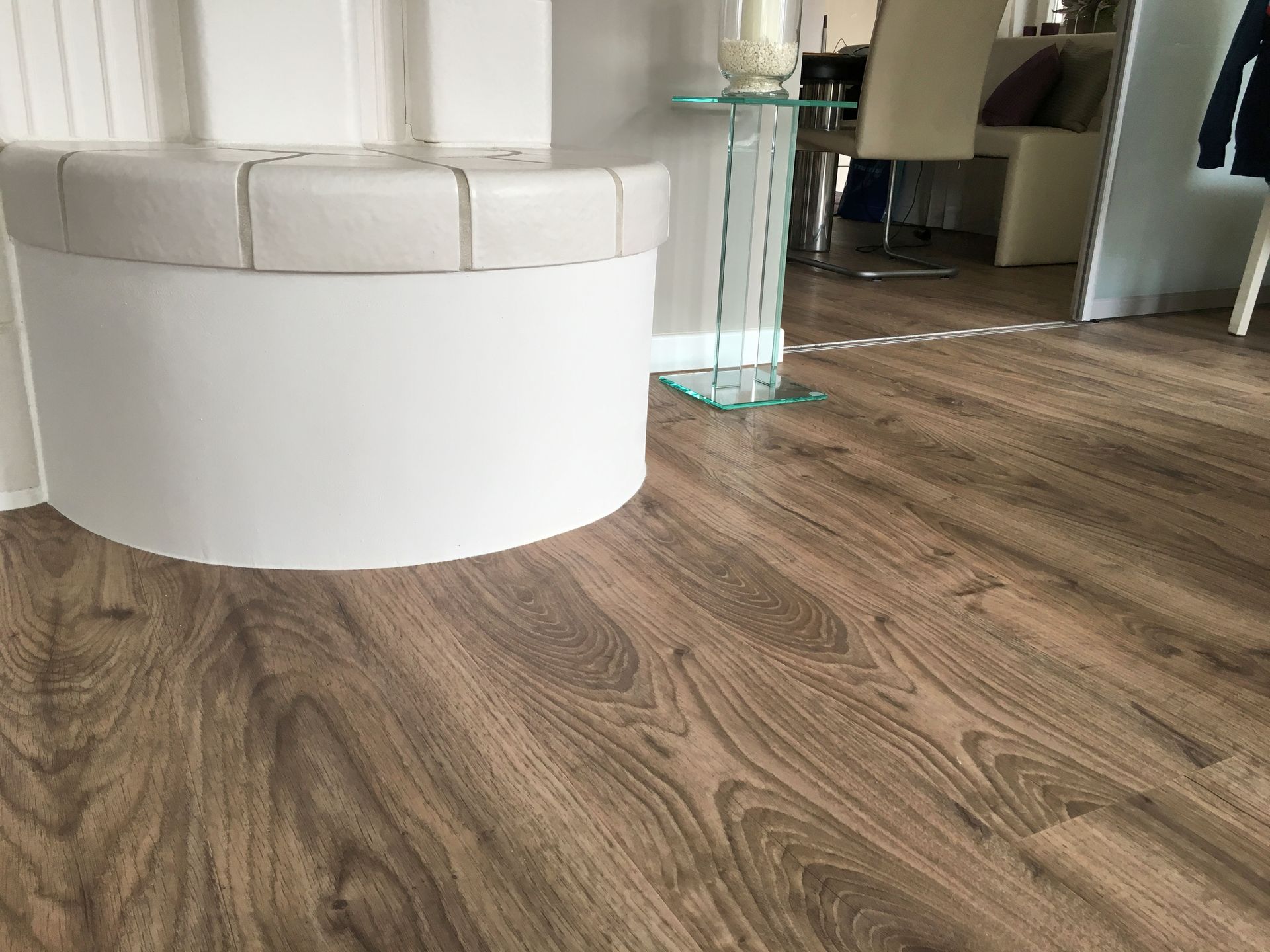 Ein Holzboden in einem Raum mit einem weißen Hocker