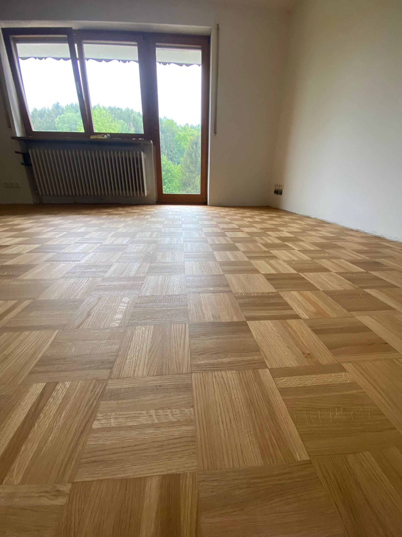 Ein leerer Raum mit einem Holzboden und einem Fenster