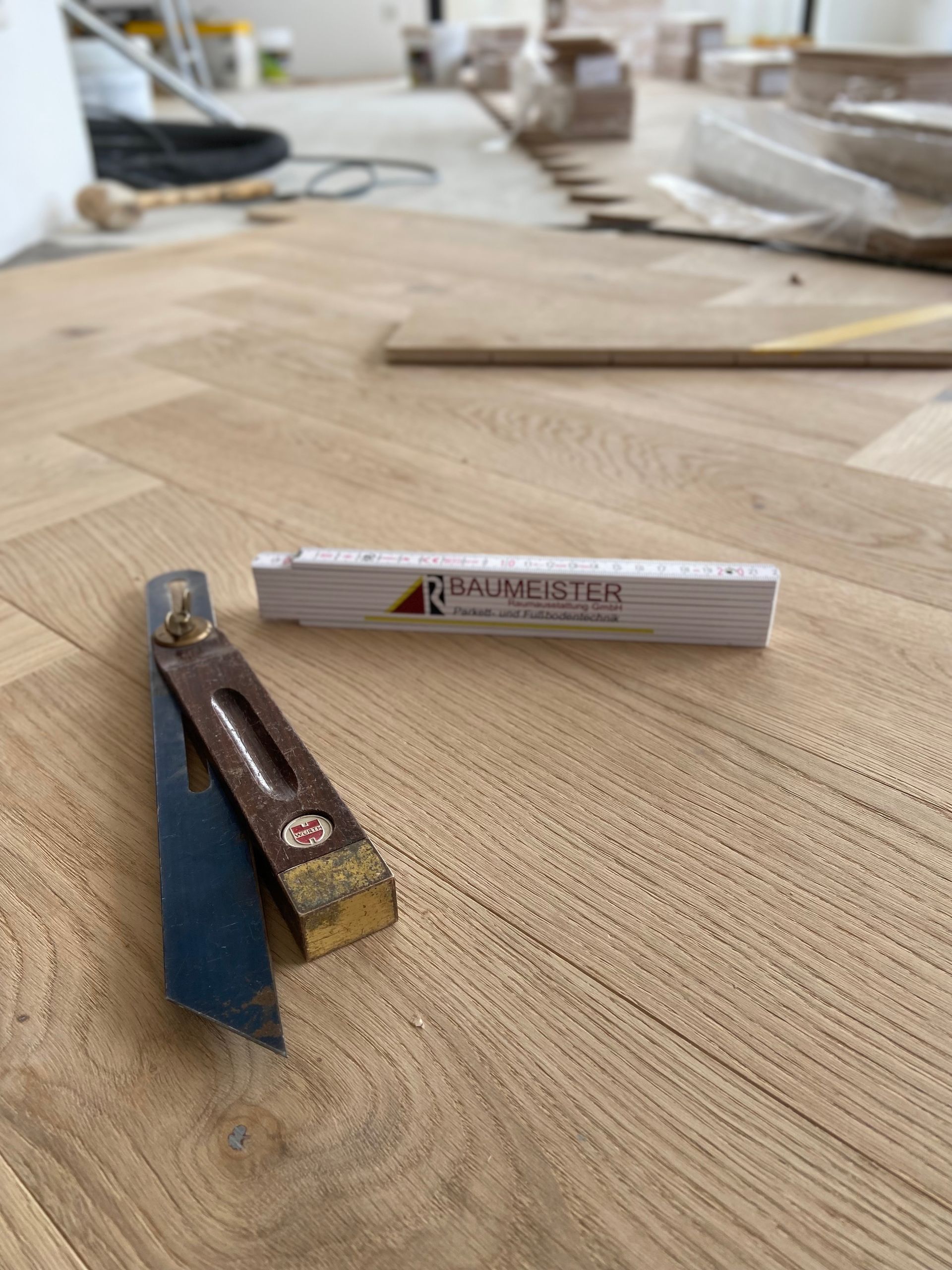 Ein Baumeister-Meter liegt auf einem Holzboden